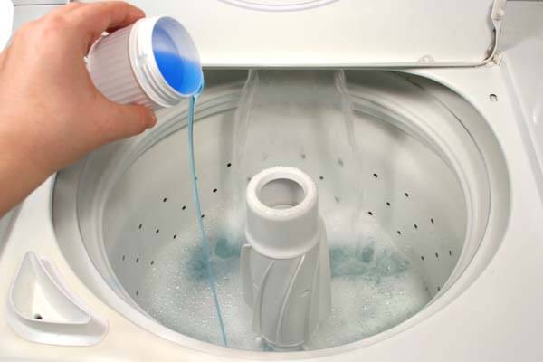 pouring laundry detergent into washer